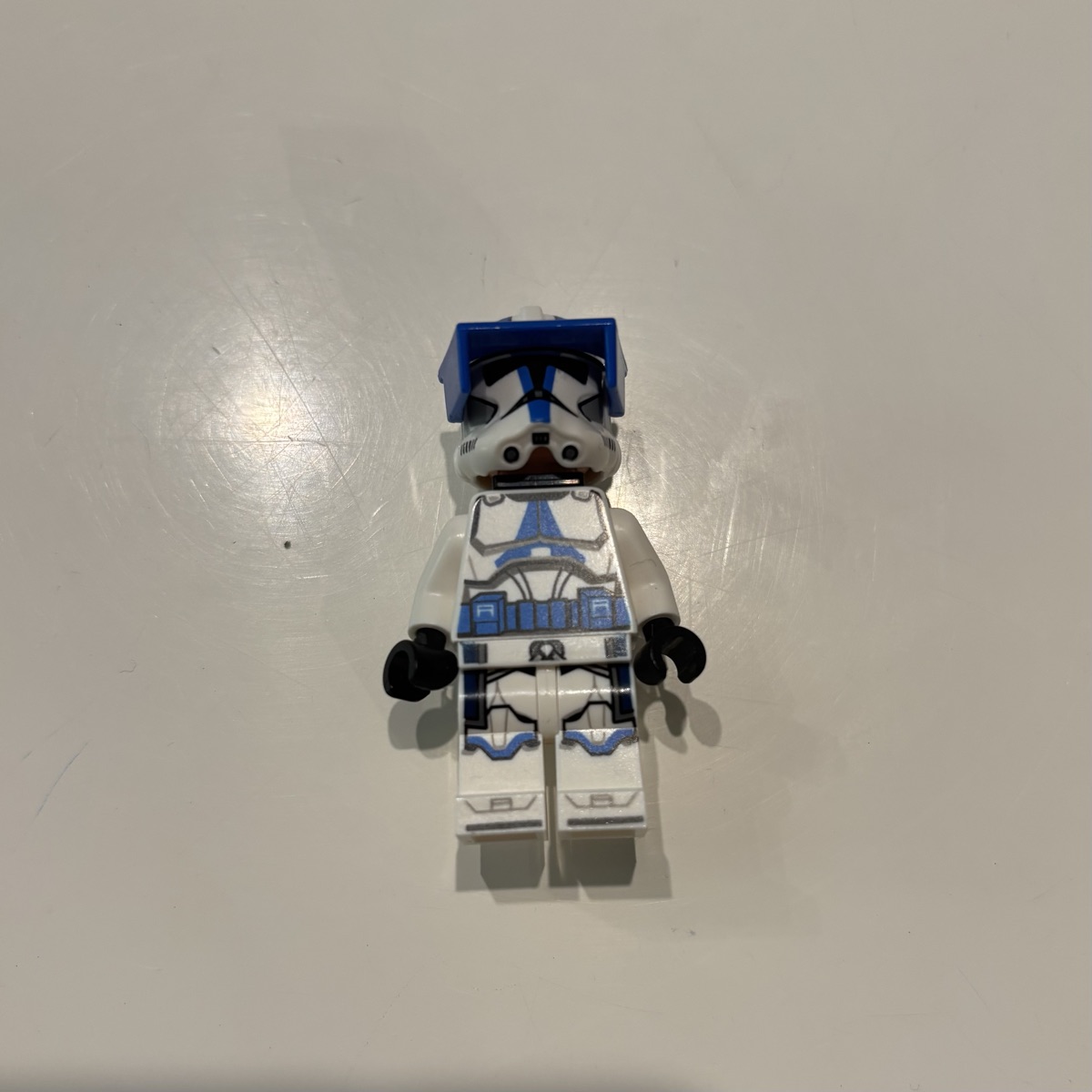 A LEGO® 501st clone trooper officer minifigure standing on white paper in soft light, photographed straight on: the clean control shot.